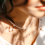 collier en perle d'eau douce porté par une jeune femme dans un jardin