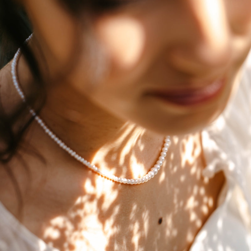 collier en perle d'eau douce porté par une jeune femme dans un jardin