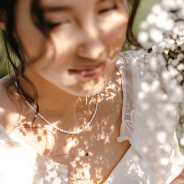 collier en perle d'eau douce porté par une jeune femme dans un jardin